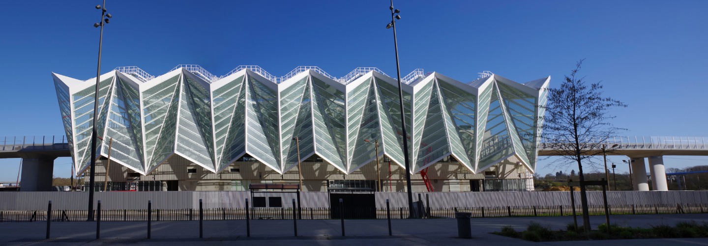 Façade moderne en verre plissé d'un bâtiment tertiaire sous un ciel bleu