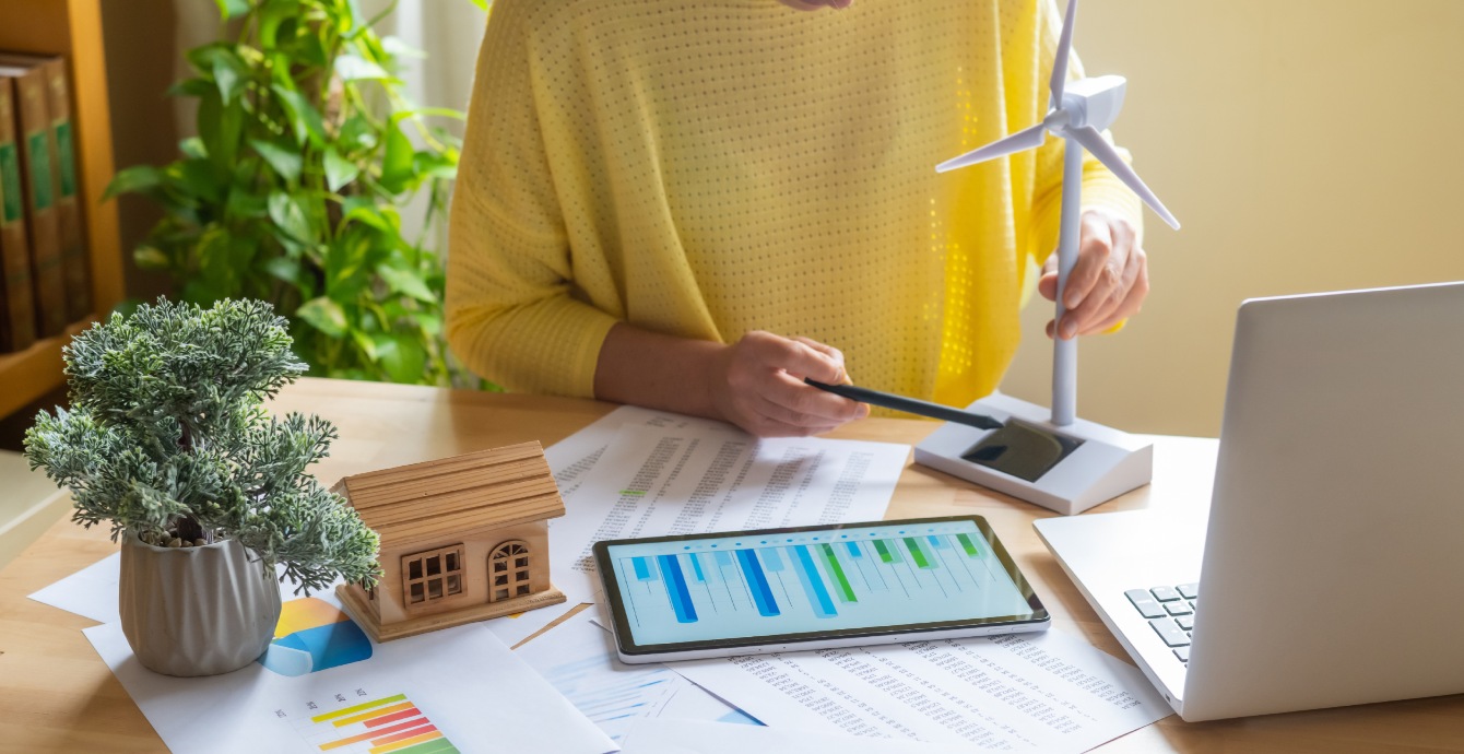 Étude énergétique sur tablette avec maquette d'éolienne et de maison sur un bureau